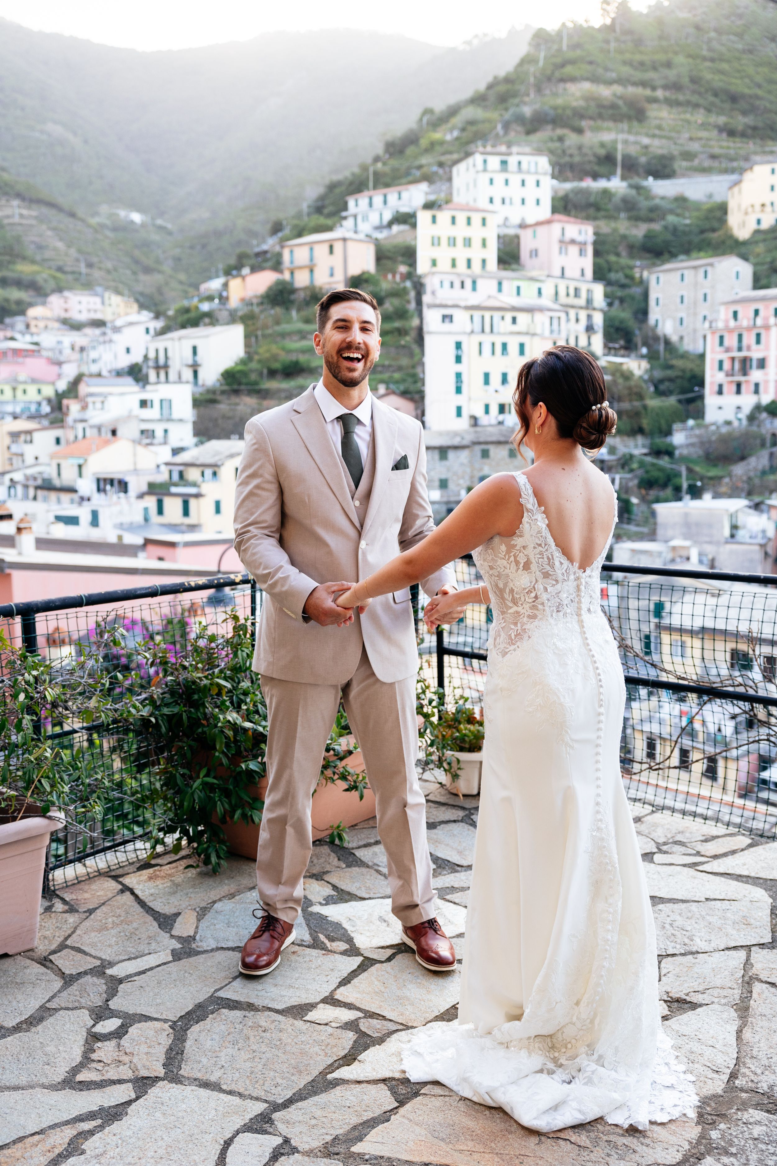 A couple shares a romantic moment on a stone terrace overlooking the colourful hillside buildings of Cinque Terre, Italy at their elopement