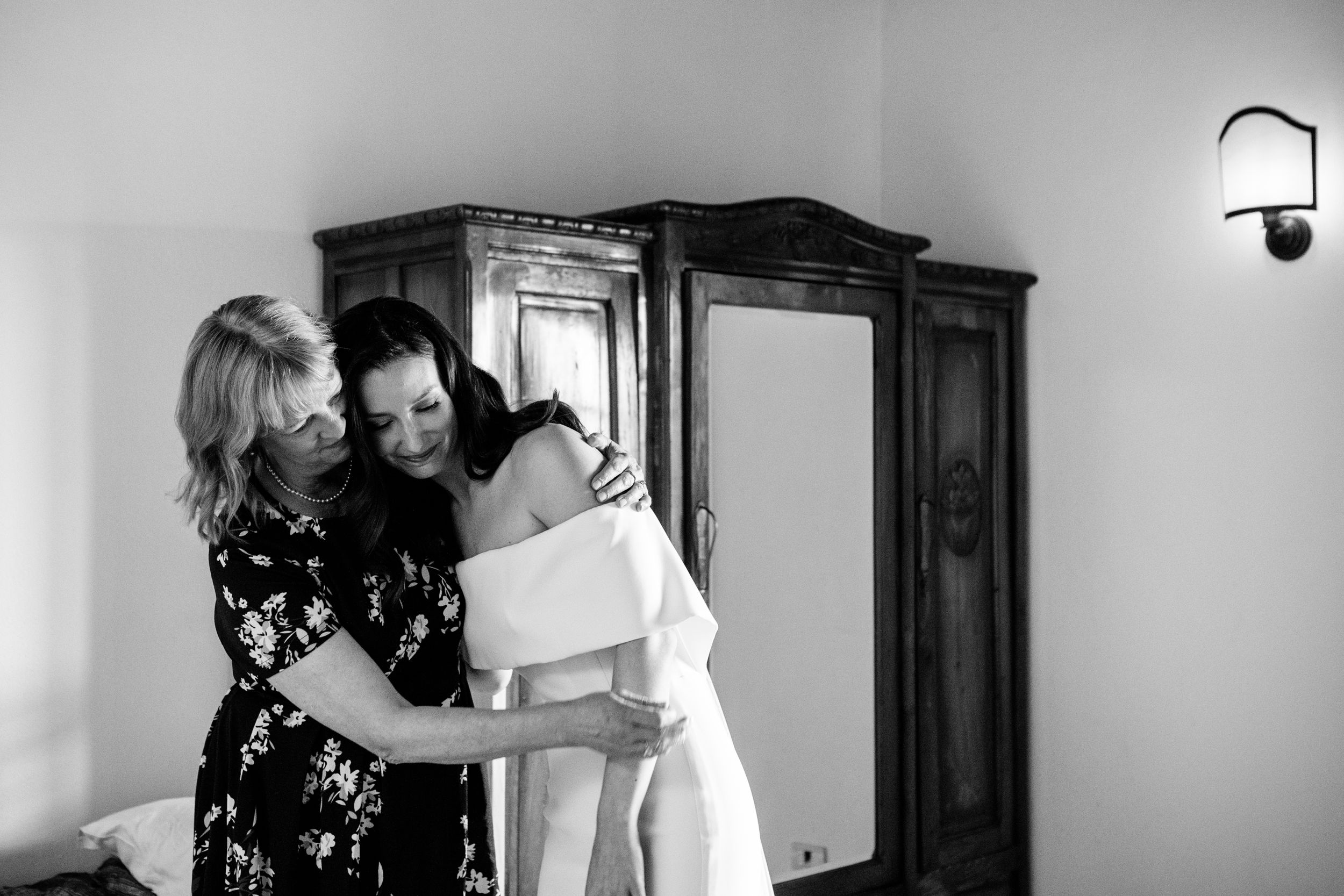 A bride and her mother share an emotional embrace before a wedding in Umbria in a black and white photograph.