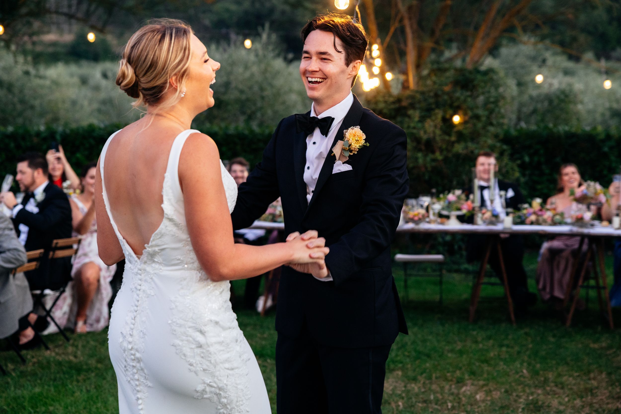 A couple shares their first dance on a lawn at a romantic outdoor wedding reception at dusk at Villa Le Bolli in Tuscany.