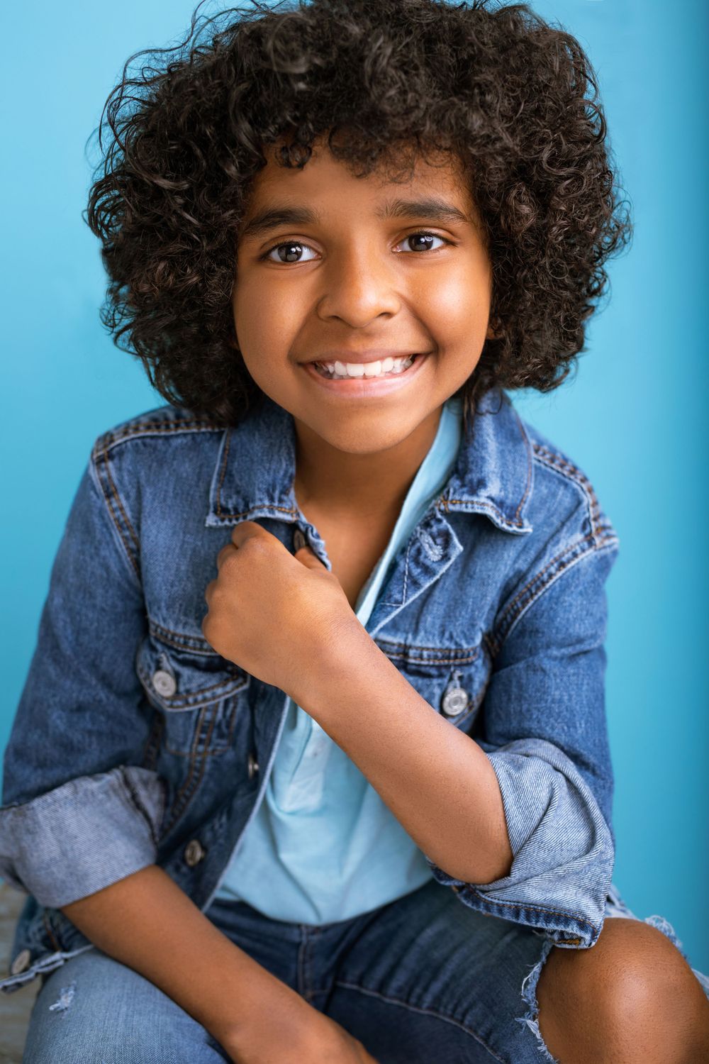 headshot portrait of a little boy with a big smile and curly hair