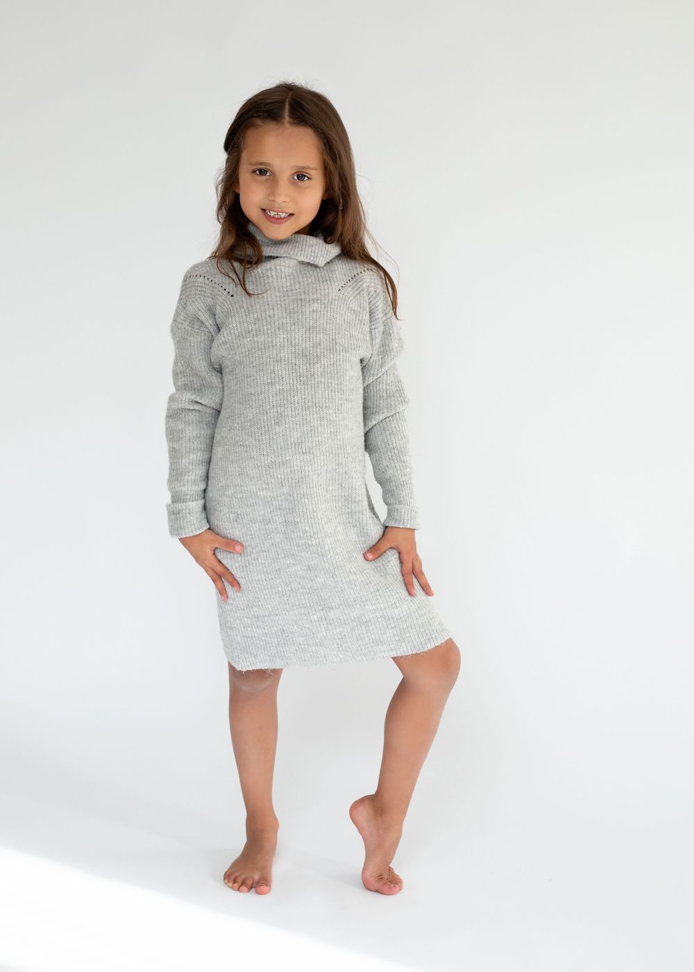 A model wearing a cozy grey sweater dress poses against a white background.