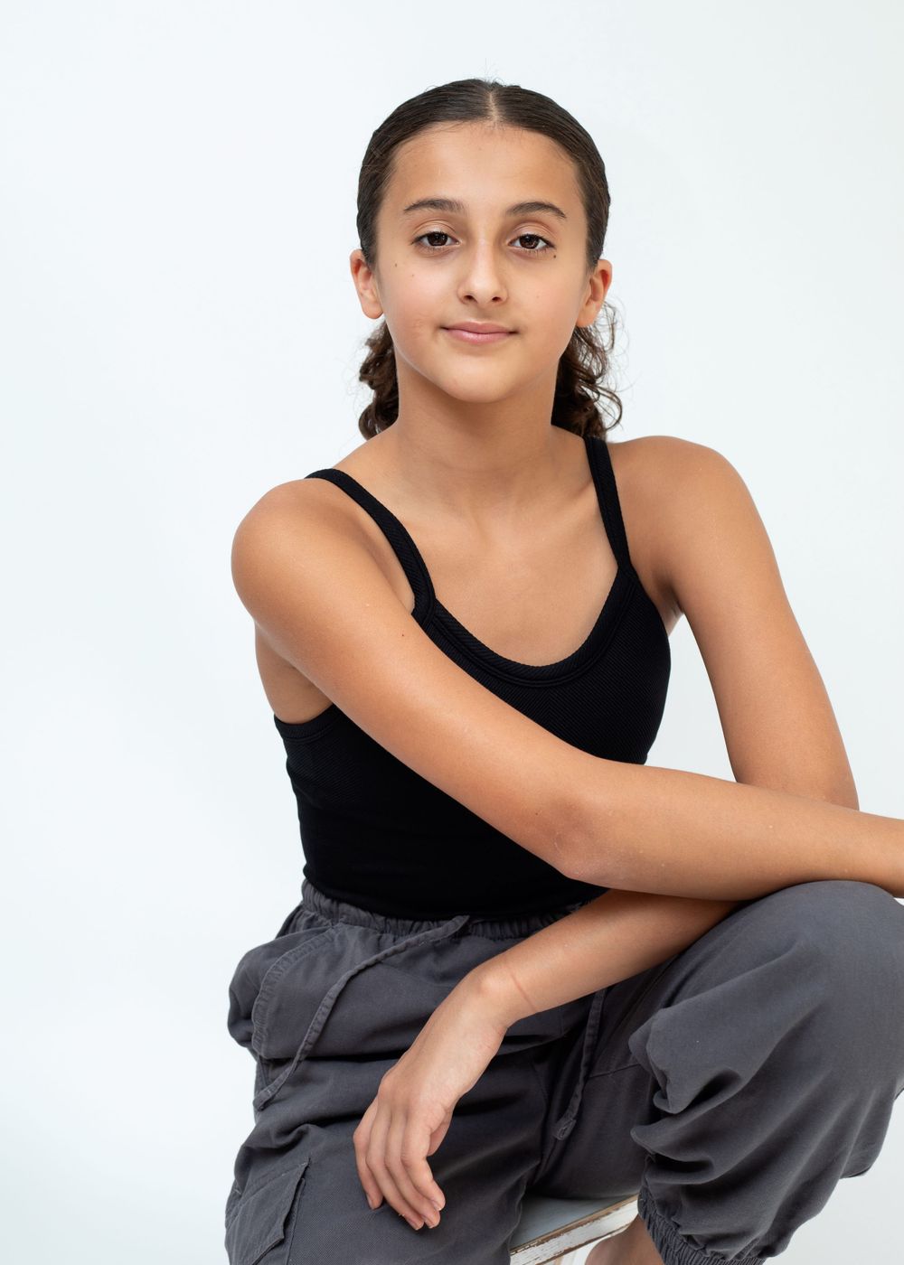 Athletic figure in black tank top strikes graceful pose against white backdrop.