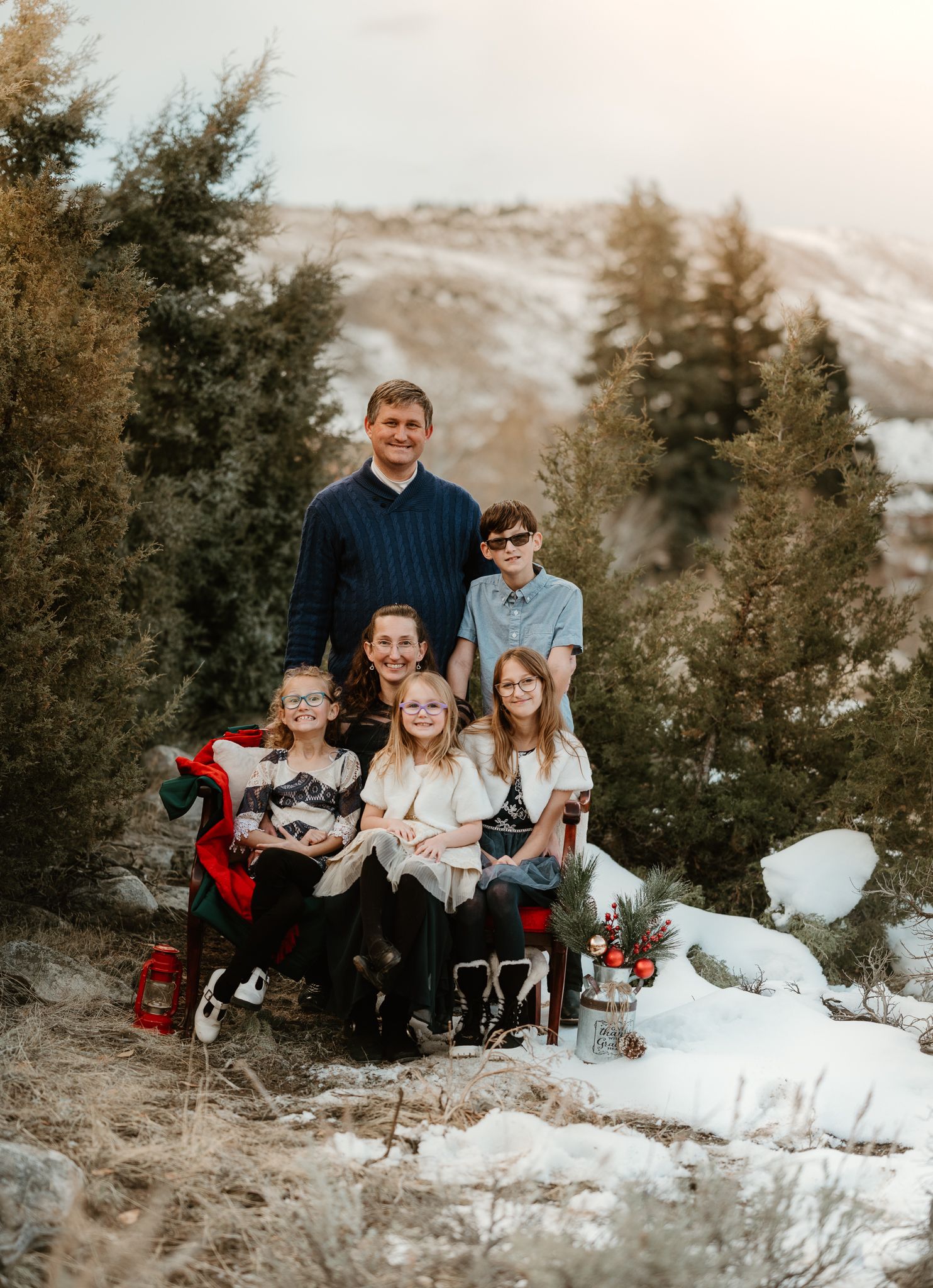 A group portrait of people sitting together in a snowy winter landscape with pine trees.