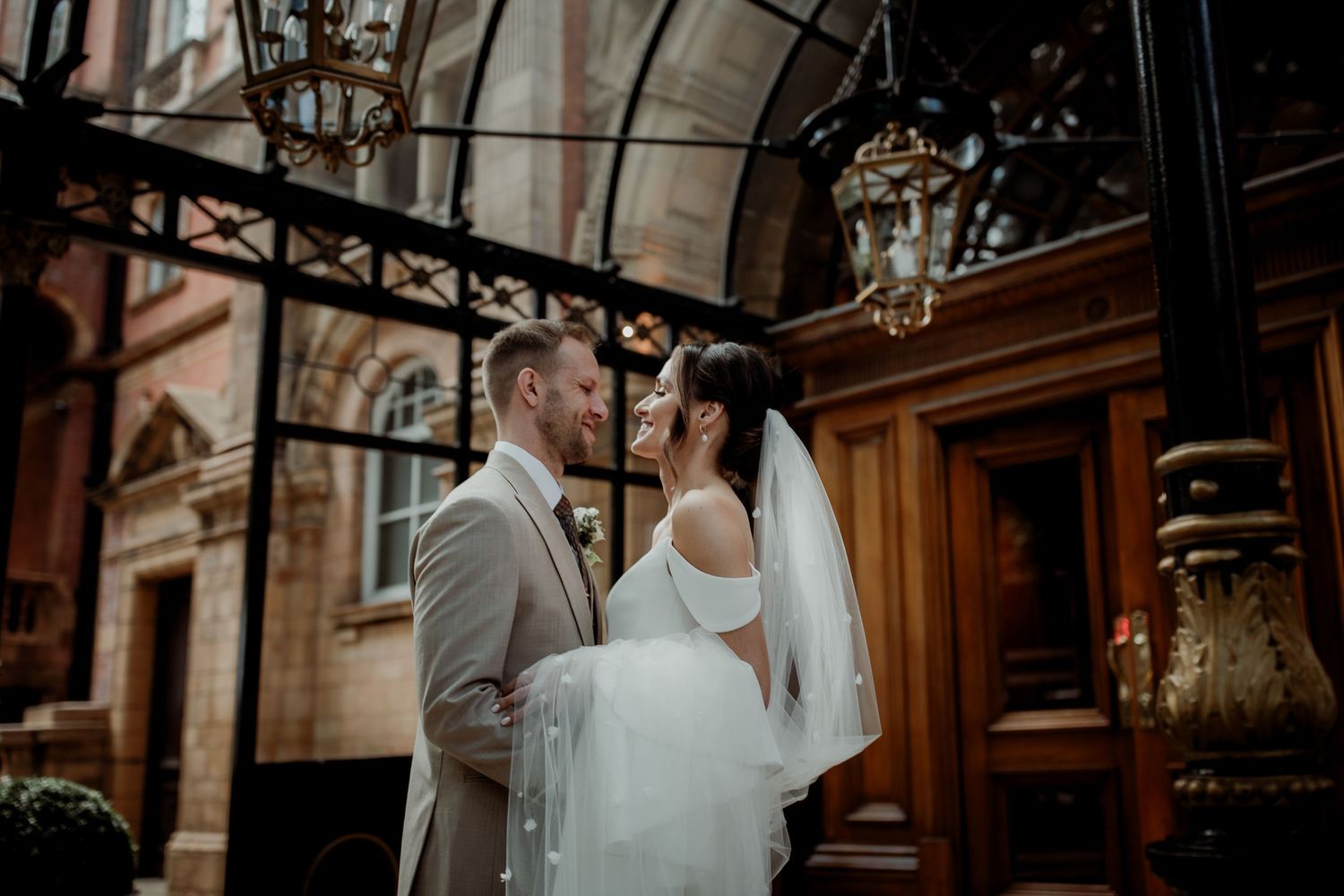 A romantic wedding couple shares an intimate moment outside an elegant historic building with ornate architectural details.