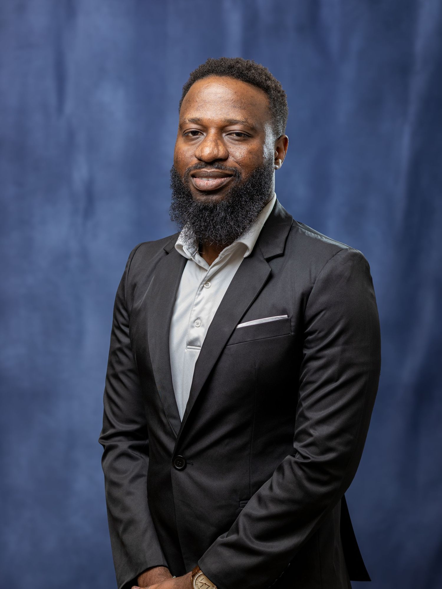 Professional headshot of someone in a business suit against a blue backdrop.
