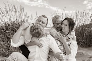 A joyful moment shared on a beach with tall grass in the background.