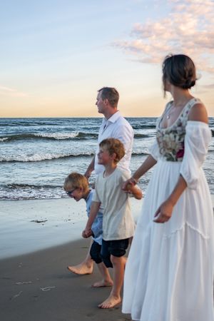 Family standing together at beach during sunset with waves rolling in.