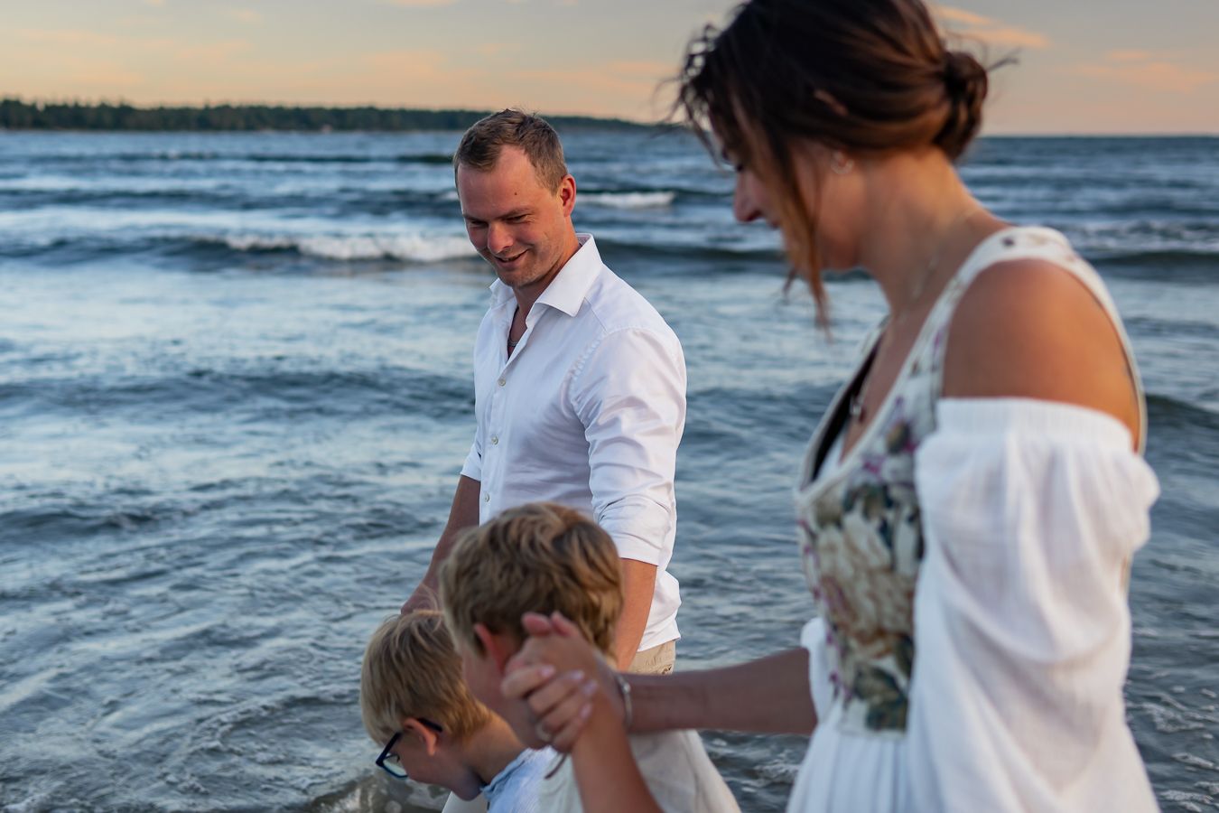 Family enjoying evening together at ocean shore during sunset.