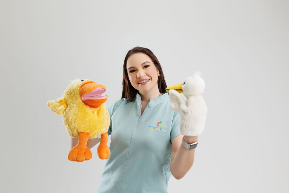 Person in aqua scrubs demonstrating hand puppets against white background.