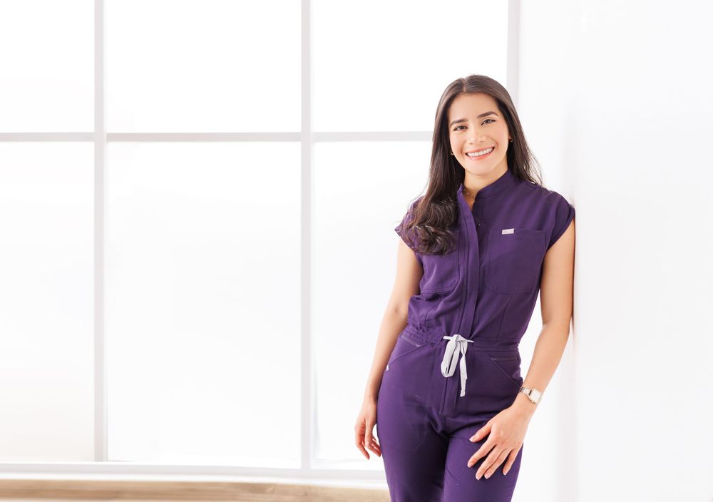 Estamos especializados en fotografía de bebés y familia Woman in purple athletic wear posing confidently against white background.