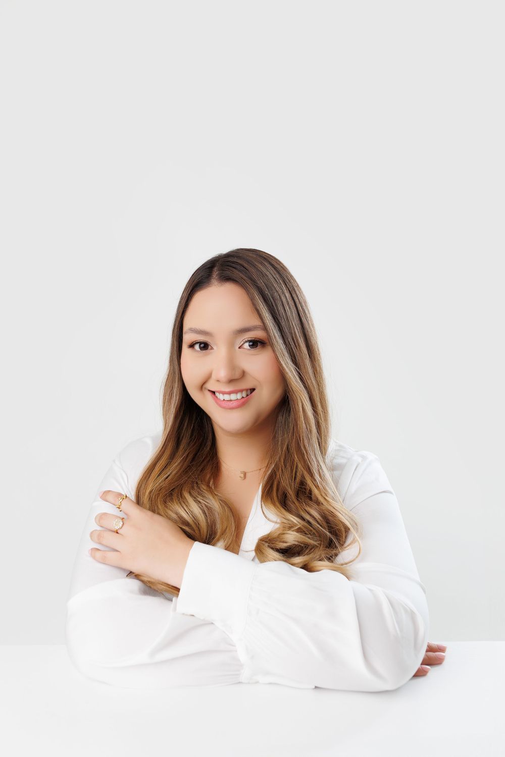 Professional headshot of woman in white top against light background.