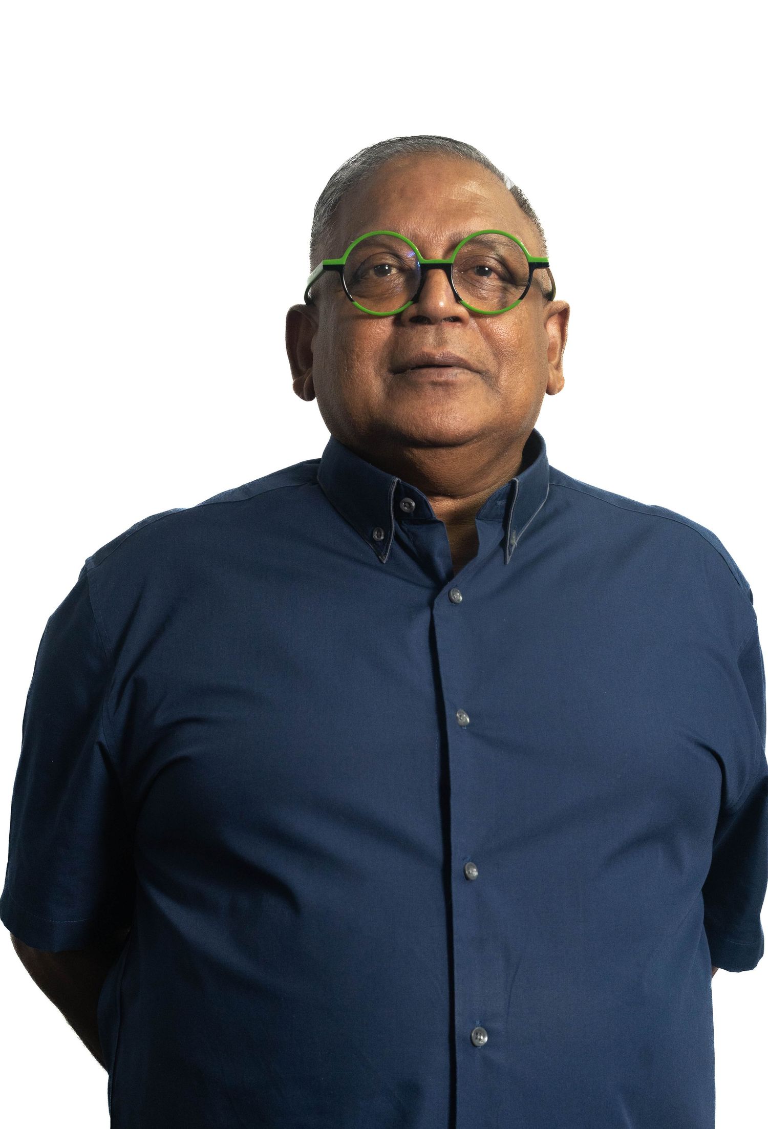 Professional headshot of person wearing round glasses and navy blue collared shirt against light background.