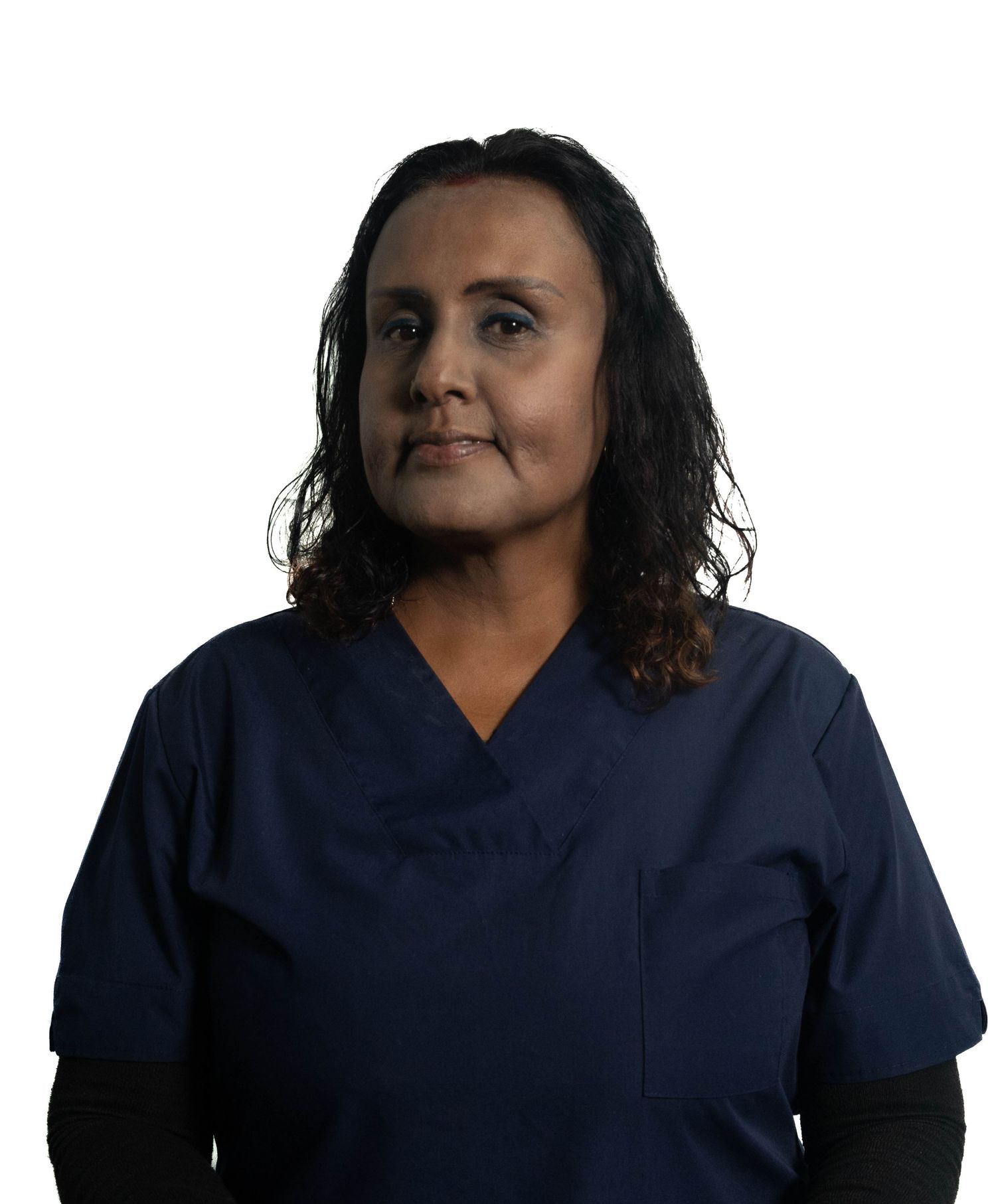 Healthcare worker in navy blue scrubs poses for professional portrait against white background.