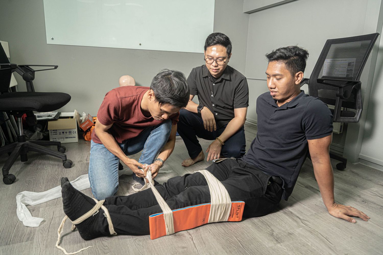 Healthcare workers demonstrating proper leg splinting technique during training session.