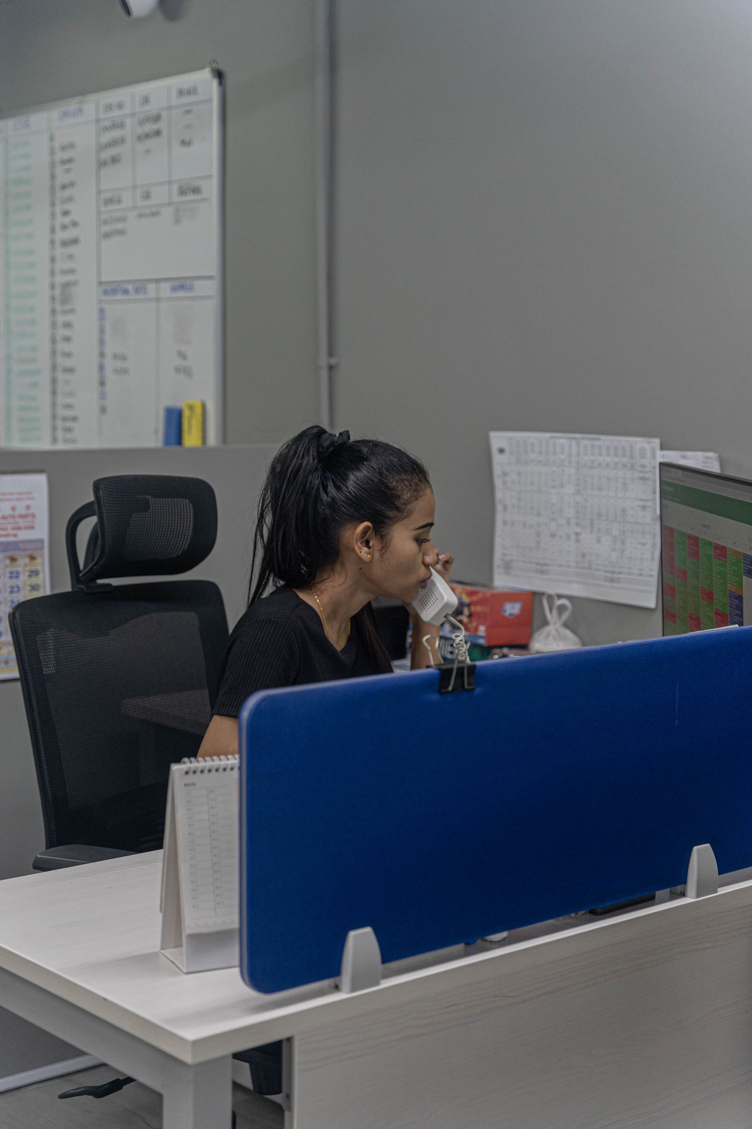 Professional working at desk with computer monitors and office supplies in corporate setting.