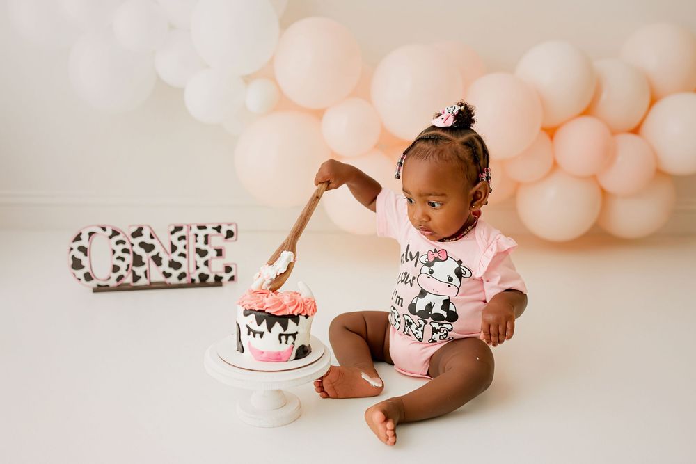 Baby girl cake smash session with cow themed cake and pink balloons at Summerville SC photography studio