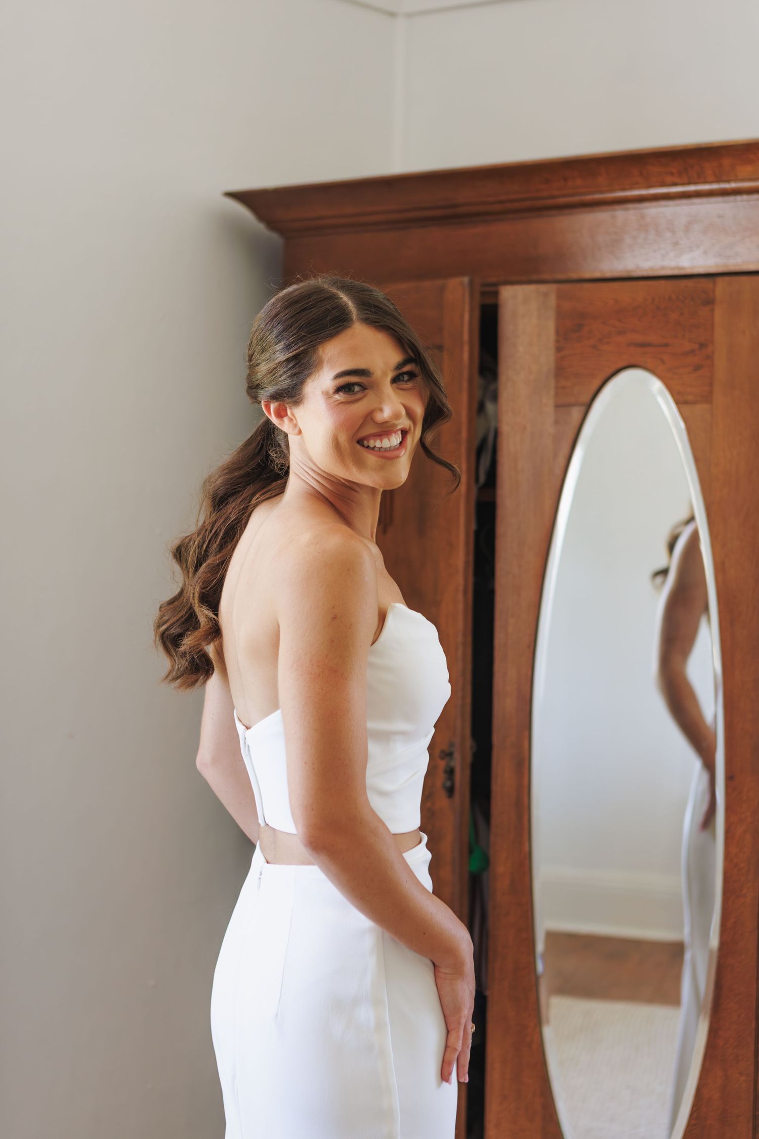 bride in wedding dress turns and looks over her shoulder smiling