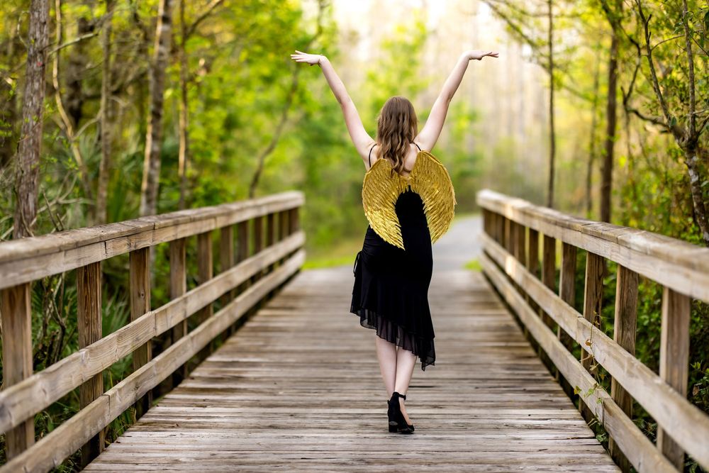 A sequence of photos showing someone in a black dress walking away on a wooden boardwalk through lush greenery.