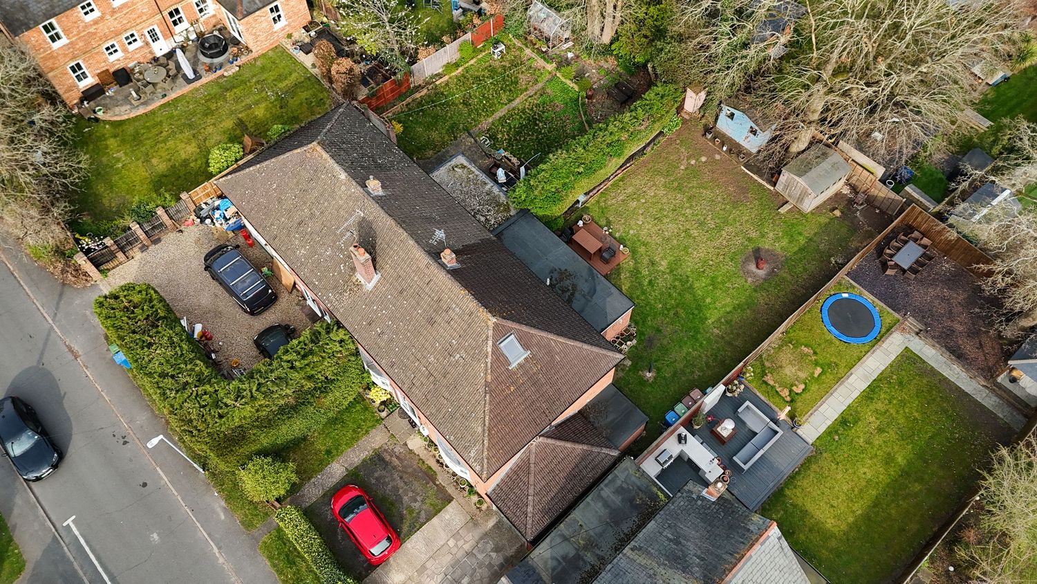 Aerial view of residential neighborhood with houses, gardens, and driveways captured by drone photography.