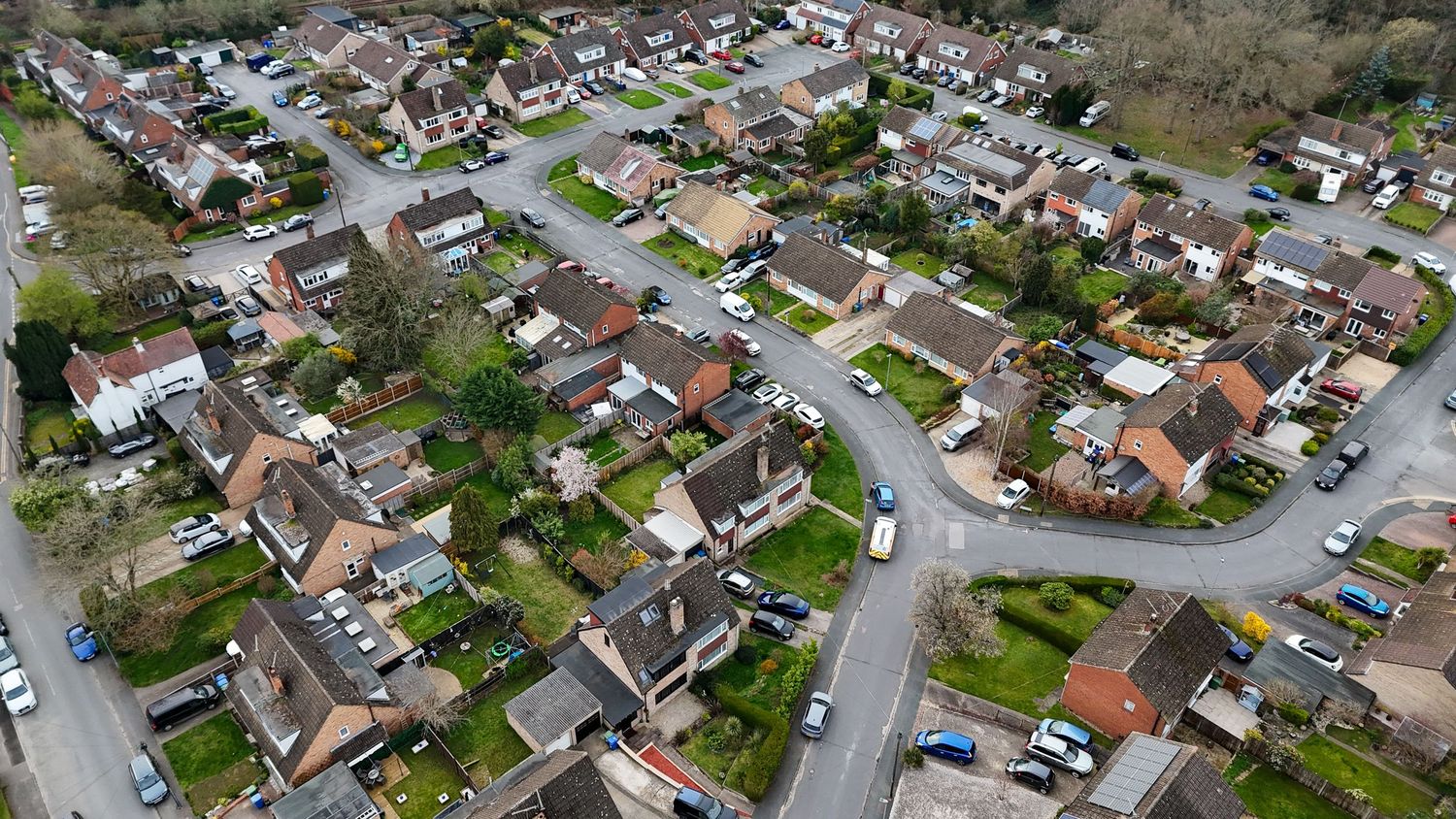 Aerial panoramic view of suburban neighborhood with residential houses and winding streets surrounded by trees.