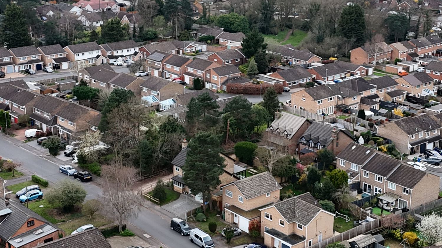 Aerial panoramic view of a residential neighborhood with rows of houses and winding streets on a cloudy day.