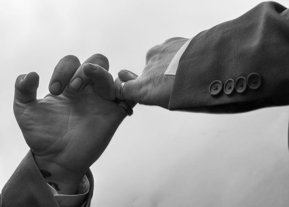 Black and white photo of a man in a suit kissing a woman's hand in a classic romantic gesture.