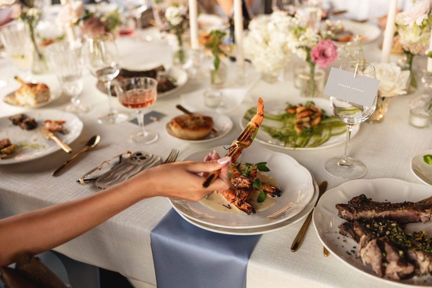 Guest serving lobster at a beautifully styled outdoor wedding reception dinner table.
