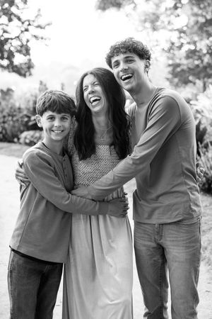 Black and white candid family photos showing joyful embraces and laughter outdoors.