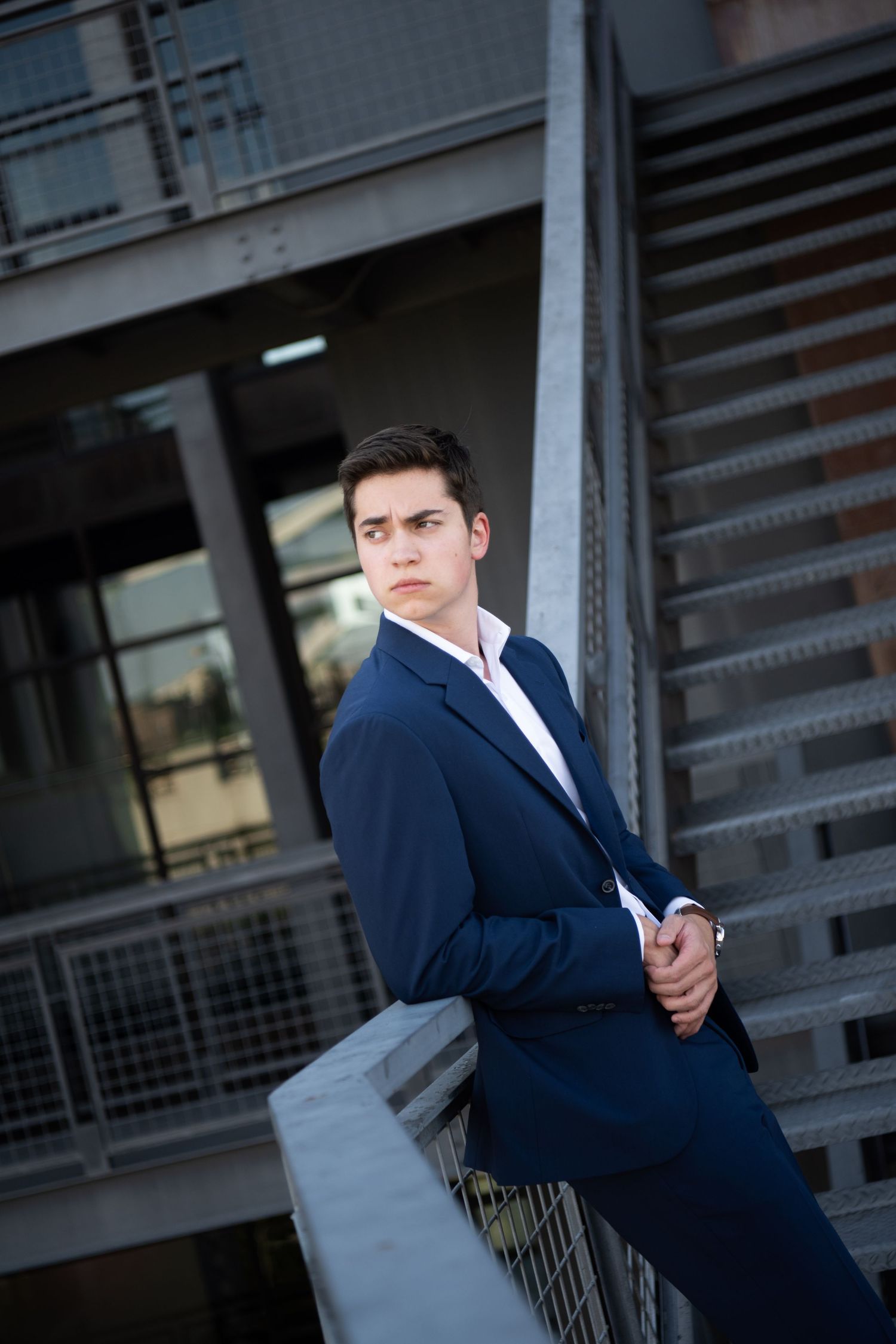 Black and white portrait series showing person in dark suit and white shirt sitting on steps in various contemplative poses.