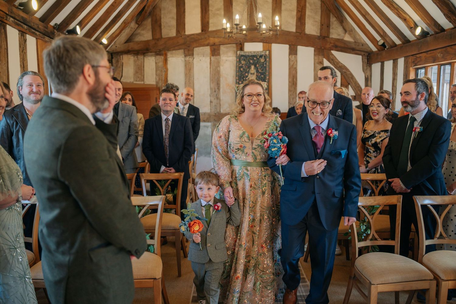 A wedding ceremony takes place in a rustic wooden barn with exposed beams and natural lighting.
