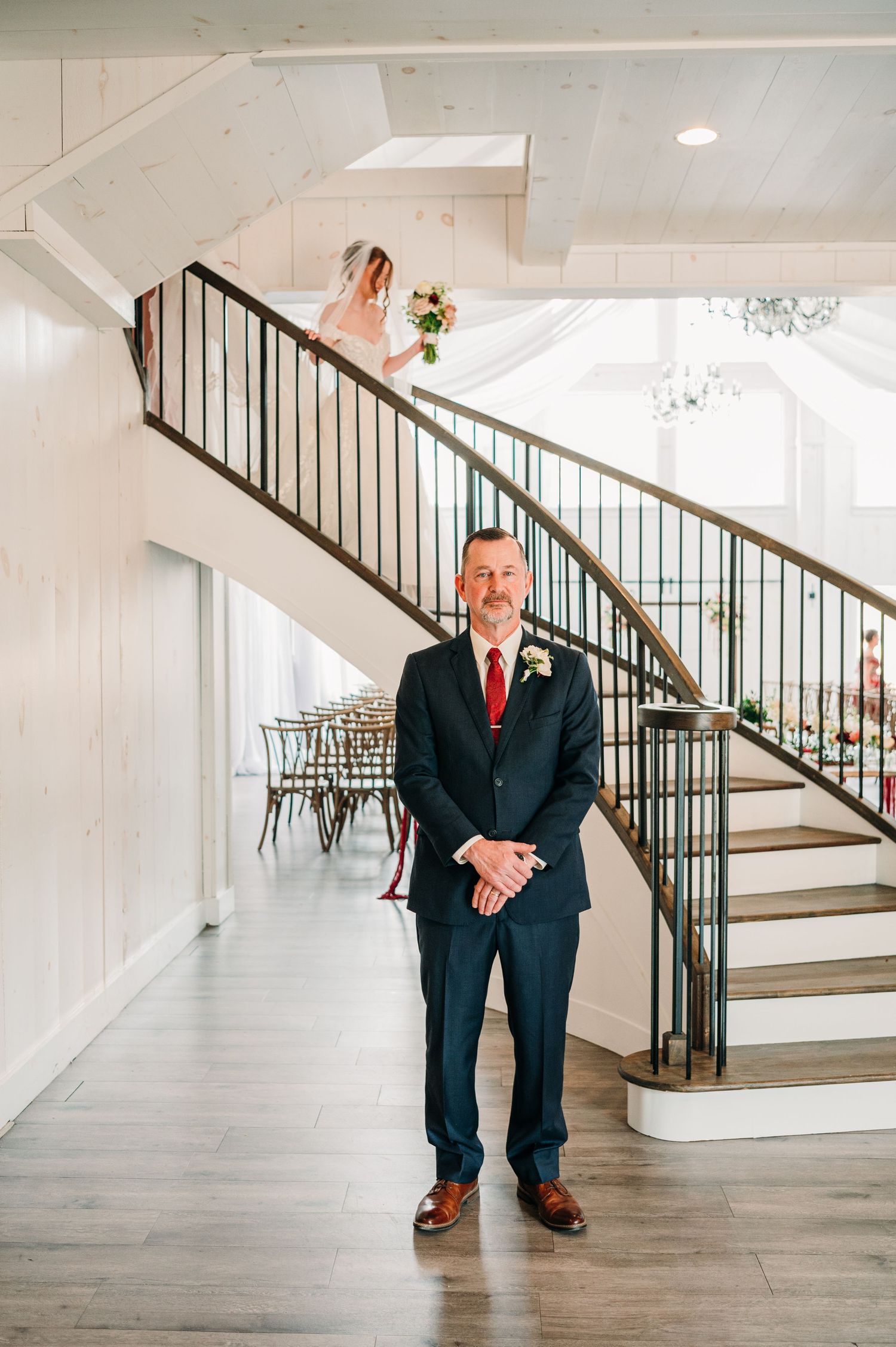 A series of five photos showing someone in a dark suit leaning against a white staircase in an elegant indoor setting.