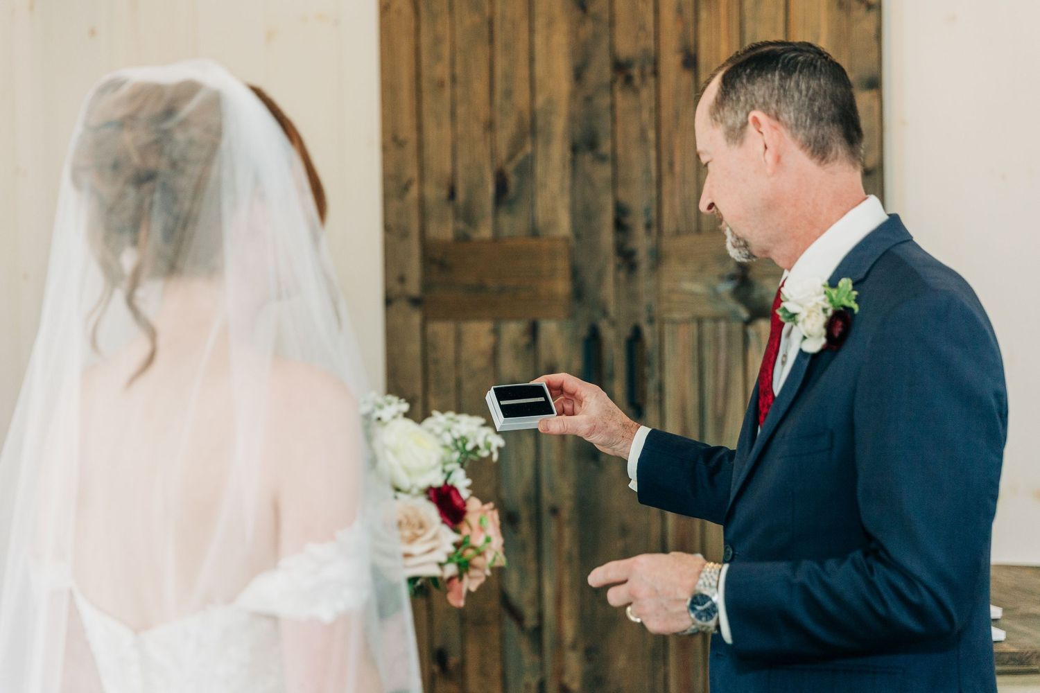 A couple shares a tender moment during their rustic barn wedding ceremony with soft natural lighting.