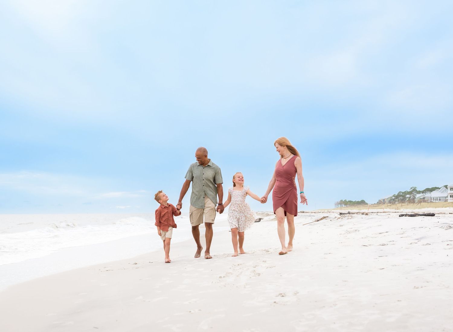 Family members play and splash together in the shallow ocean waves on a sunny beach day.