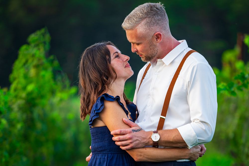 Romantic couple embraces in a lush green vineyard during sunset creating an intimate moment.