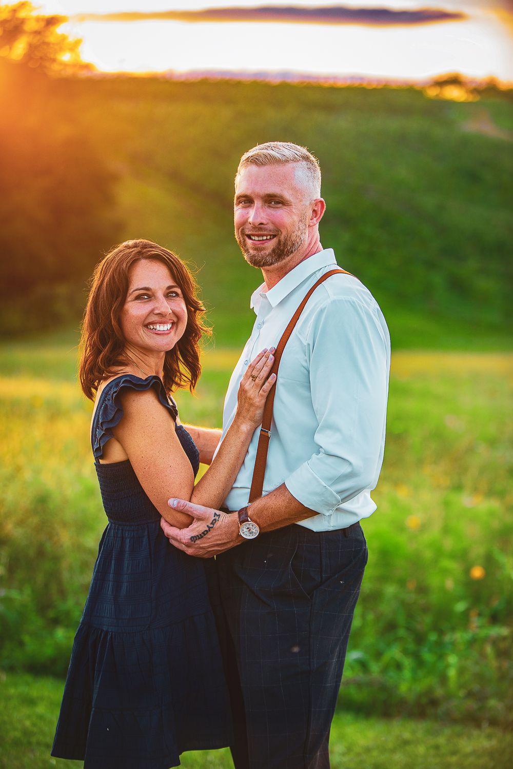 Couple shares tender moments during golden hour photoshoot in a sunlit field.
