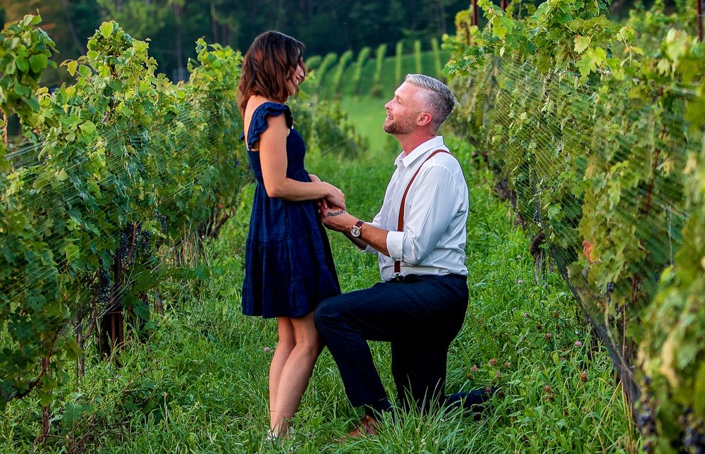 A proposal moment captured in a vineyard as a couple shares an intimate moment among the grape vines.