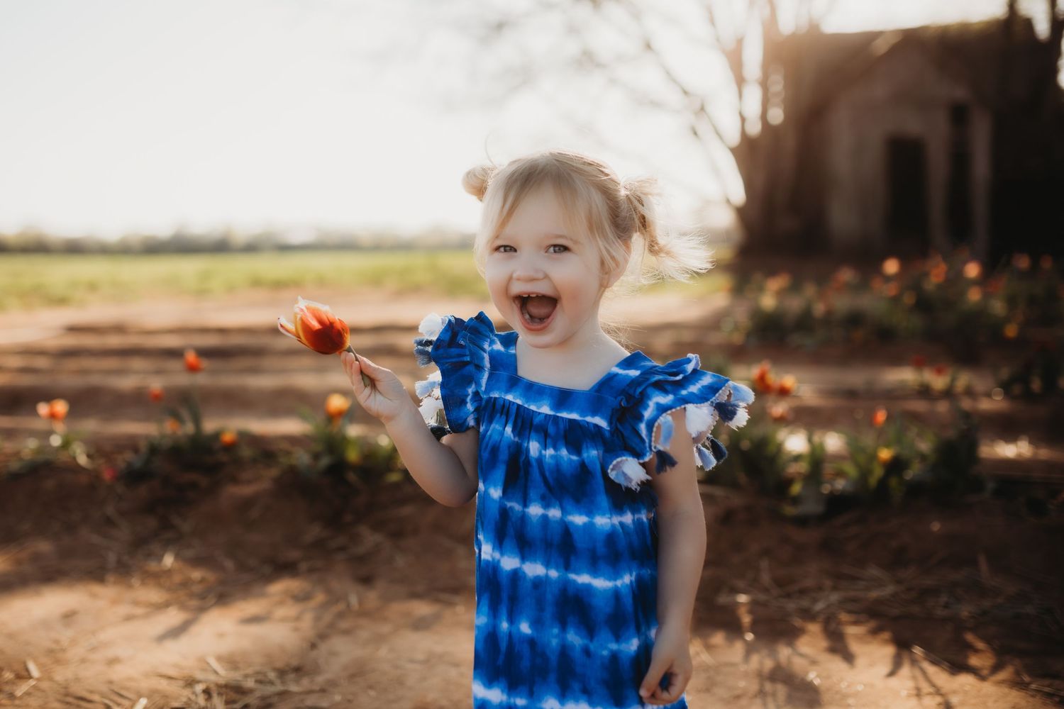 A joyful moment captured outdoors in a blue tie-dye dress on a sunny autumn afternoon.