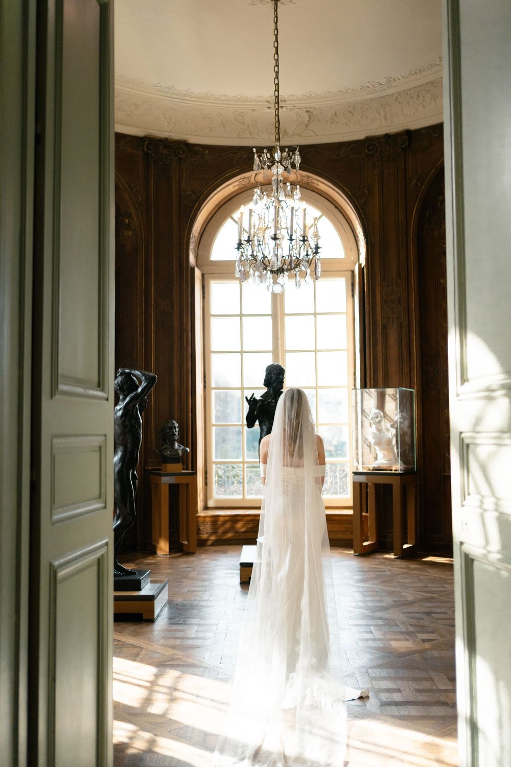 Elegant ballroom interior with arched windows, crystal chandeliers and floating white fabric decorations creating ethereal ambiance.