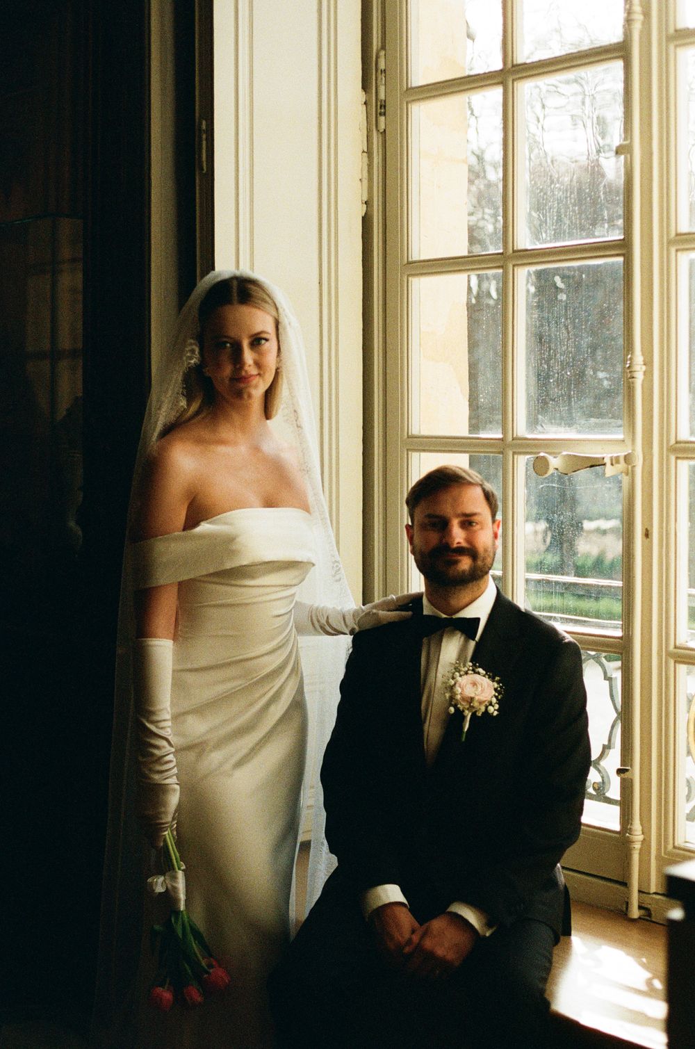 A romantic wedding photoshoot sequence by a bright window shows tender moments between a couple in formal attire.