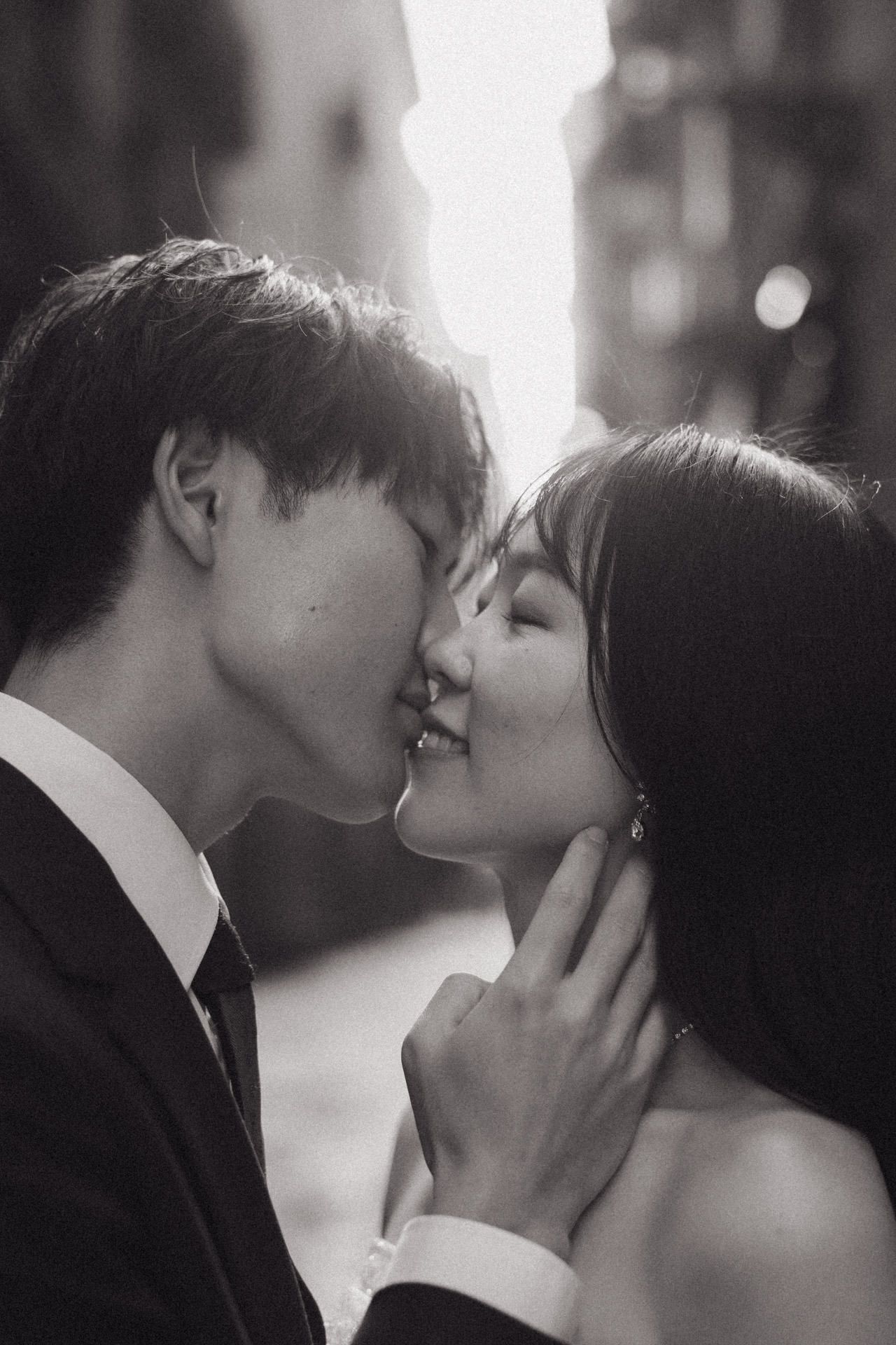 A romantic black and white photo series showing an intimate couple sharing tender kisses in soft lighting.