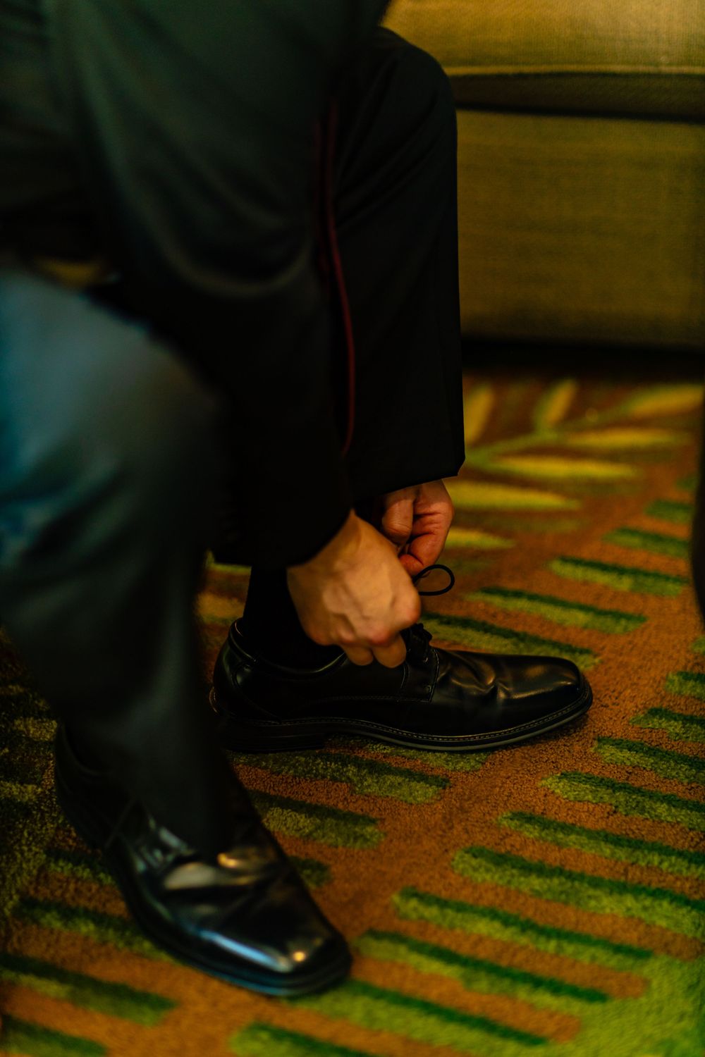 Close-up shots of formal black dress shoes on a patterned carpet.