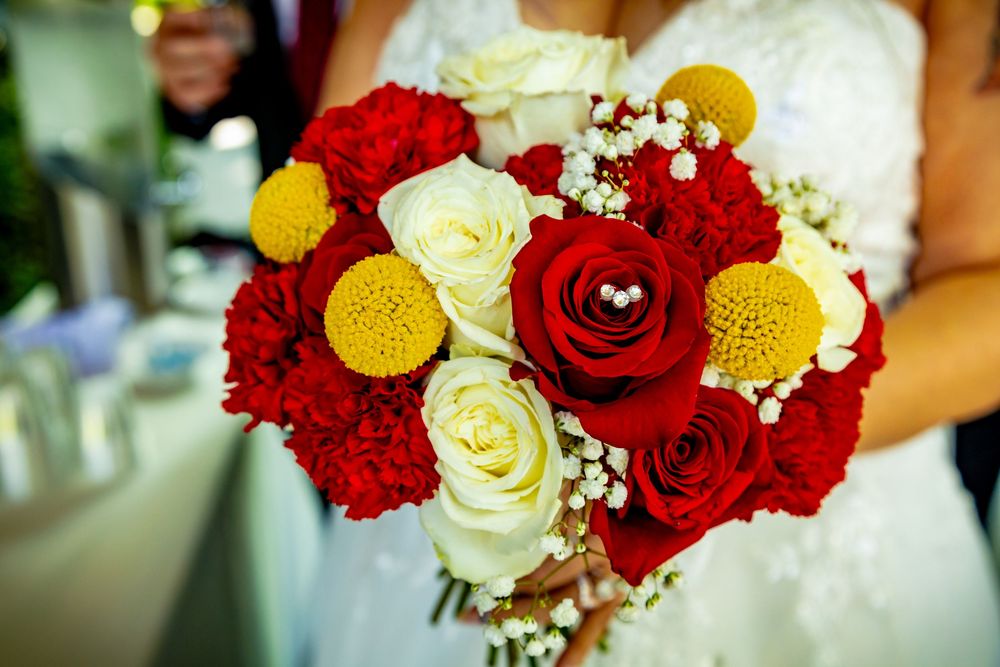 Wedding bouquet featuring red and cream roses with yellow accent flowers and baby's breath.