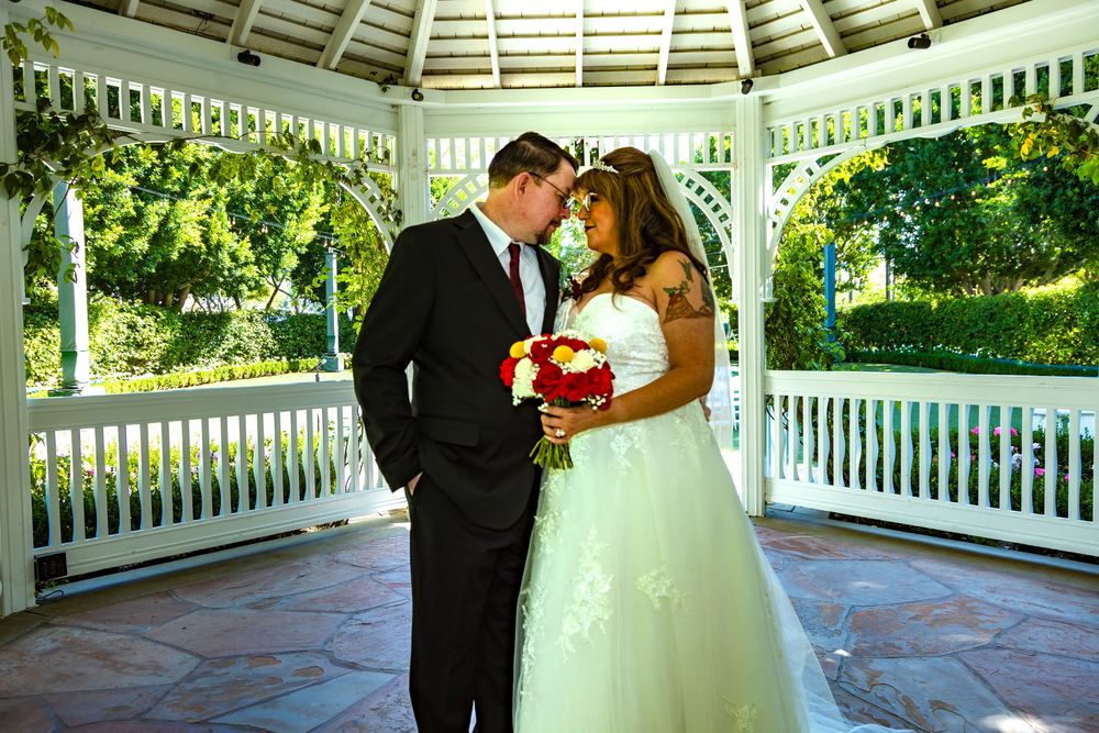 Wedding couple sharing romantic moments under a white gazebo surrounded by lush greenery.