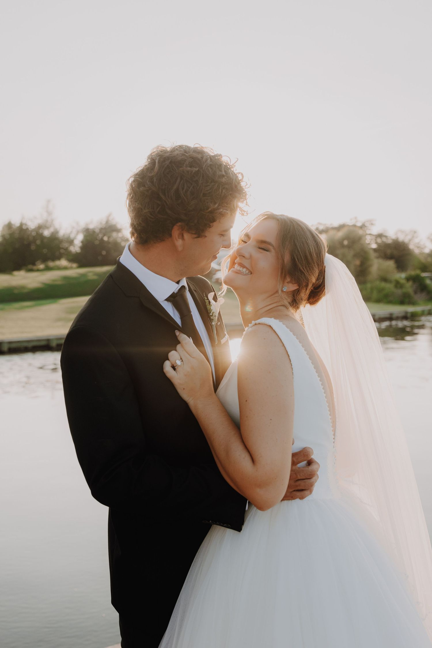 Wedding couple poses for creative panoramic photos in front of large industrial grain silos.