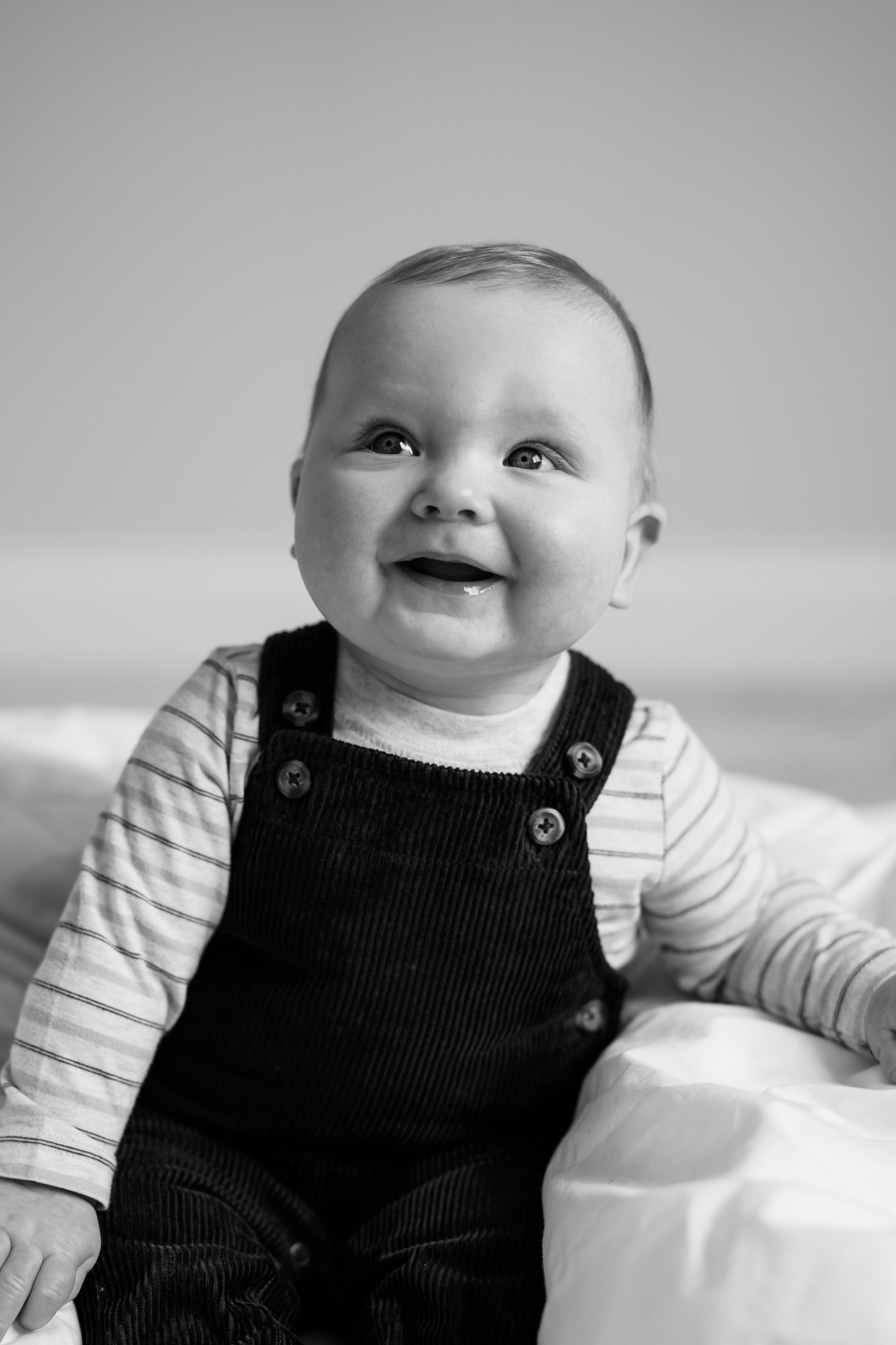 A series of black and white photos showing a baby in striped shirt and overalls looking upward with joyful expressions.