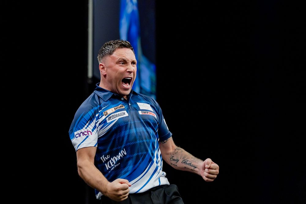 A man with tattoos and a blue jersey is shouting and celebrating on a stage.