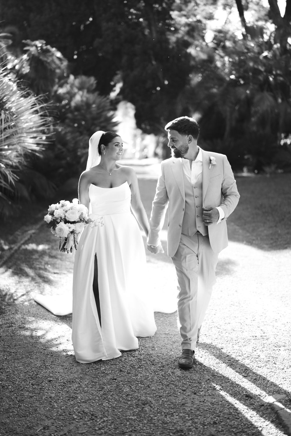 Bride and groom strolling hand in hand in the park of Villa Nobel in Sanremo during their wedding photoshoot.