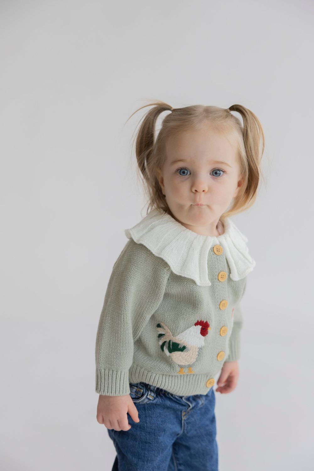 toddler girl in a sweater making a silly face for a studio photoshoot