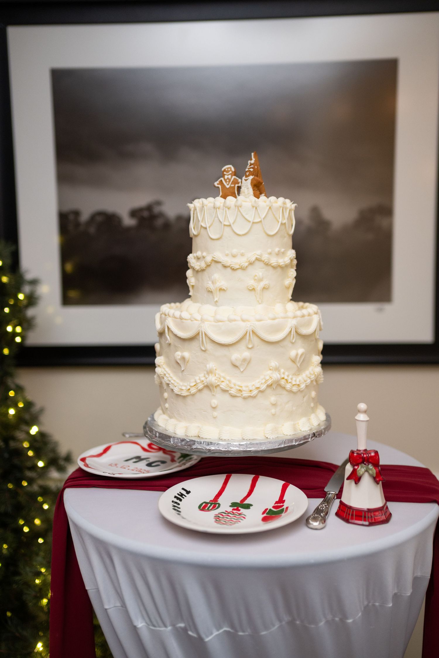 A traditional white wedding cake with ornate piping details and a gold topper displayed on a white tablecloth.