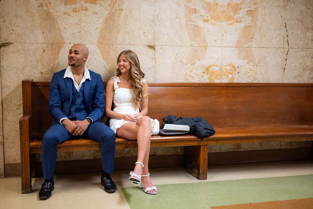 A couple's feet in formal shoes sitting on a wooden bench showing their wedding attire.
